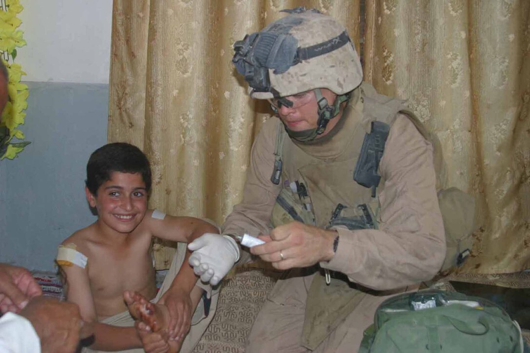 Petty Officer 2nd Class Jonathan E. Knotts, corpsman, MAP, Charlie Company, 1/3, checks a local Iraqi boys wound after he was wounded by a rocket-propelled grenade during a firefight in Haqlaniyah June 10.