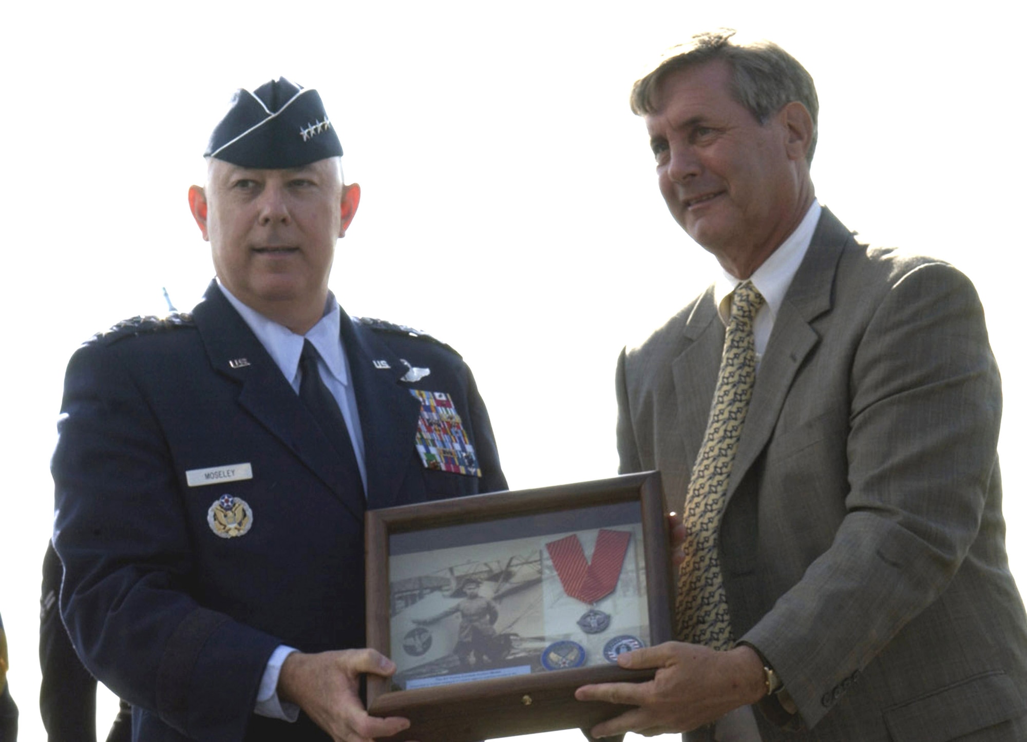 Air Force Chief of Staff T. Michael Moseley hands a shadowbox of the Air Force Combat Action Medal to Tom Gilpin, the grandson of Air Force pioneer Brig. Gen. William "Billy" Mitchell, June 12 in Arlington, Va. The AFCAM takes its design from the markings on General Mitchell's aircraft and medal was designed for Airmen who have been directly in harm's way, engaging enemy forces. The decoration is the first of its kind for the Air Force. (U.S. Air Force photo/Staff Sgt. J.G. Buzanowski)