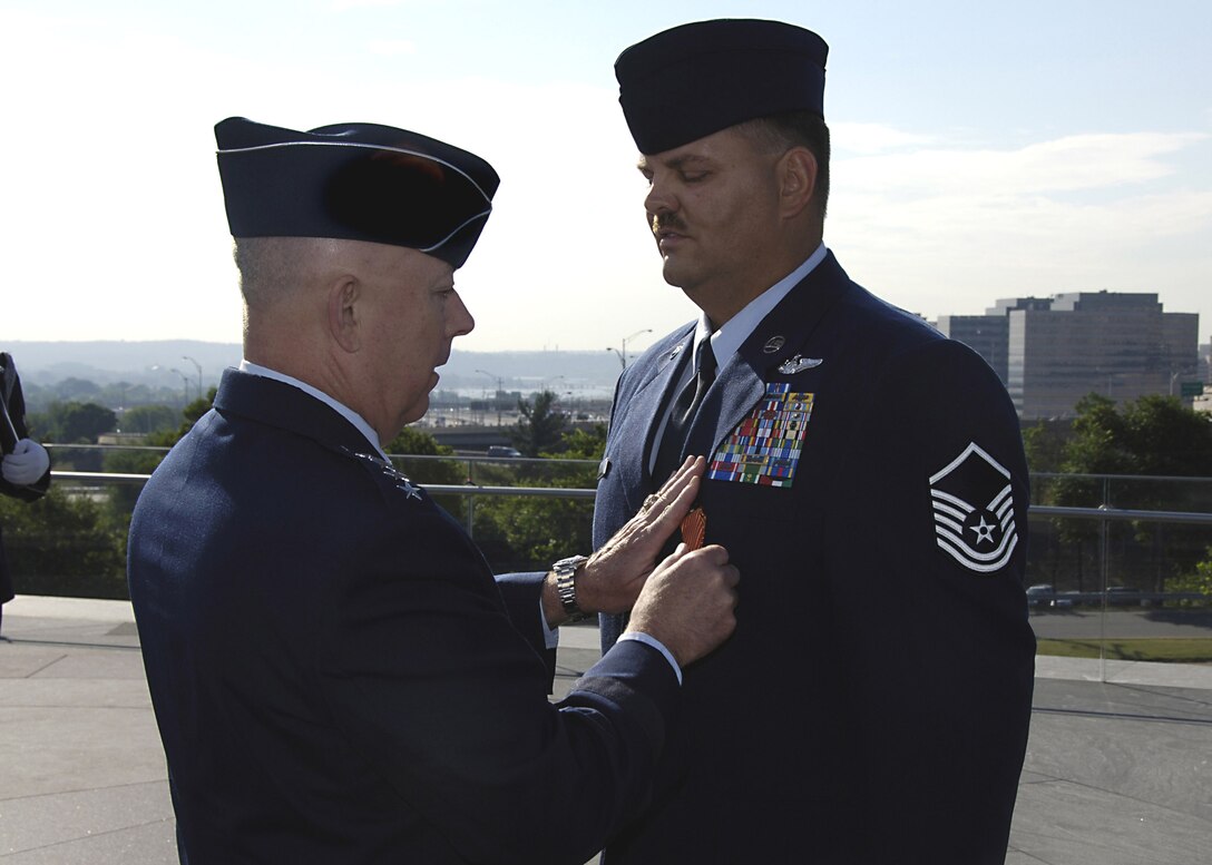 Air Force Chief of Staff Gen. T. Michael Moseley awards an Air Force Combat Action Medal to Master Sgt. Byron Allen at the Air Force Memorial June 12 in Arlington, Va., June 12. Sergeant Allen was one of six Airmen to receive the medal, awarded to Airmen who have been directly in harm's way, engaging enemy forces. Sergeant Allen was serving as an MH-53 aerial gunner was conducting a combat resupply mission when his aircraft came under enemy fire. Sergeant Allen is from the 1st Special Operations Group, Hurlburt Field, Fla. (U.S. Air Force photo/Donna Parry)
