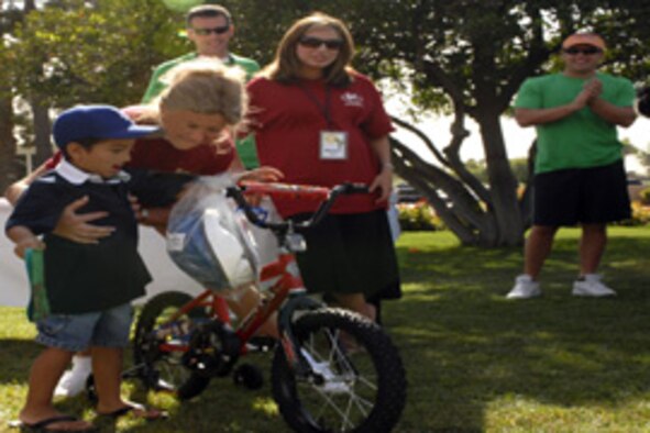 Gabriel Neal, 4, son of Staff Sgt. Kevin Neal, currently deployed to Kuwait, receives a bike Tuesday at the Wigwam resort, during the build-a-bike event sponsored by Pickering Entertainment & the Event Team.  Approximately 24 bikes, built by employees of corporations throughout the nation, were given to children of deployed servicemembers. Photo by Staff Sgt. David Miller