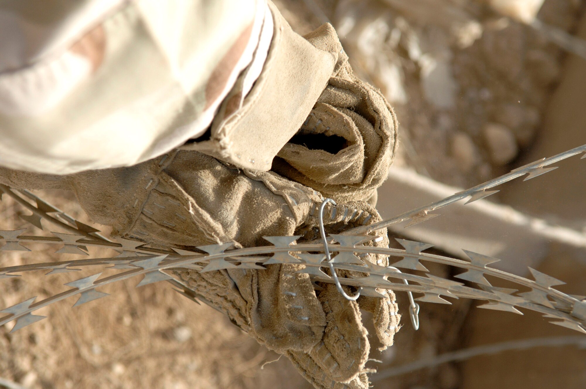 Senior Airman Margaret Wilson connects two lengths of concertina wire together June 8 on a wall to protect one of the compounds on Ali Air Base, Iraq. Airman Wilson is a member of the 407th Expeditionary Security Forces Squadron's Force Protection Flight. The flight is responsible for monitoring local and third country nationals to detect suspicious activity, augmenting security forces during increased threat levels, as well as monitoring and maintaining installation security measures.(U.S. Air Force photo/Master Sgt. Robert W. Valenca)
