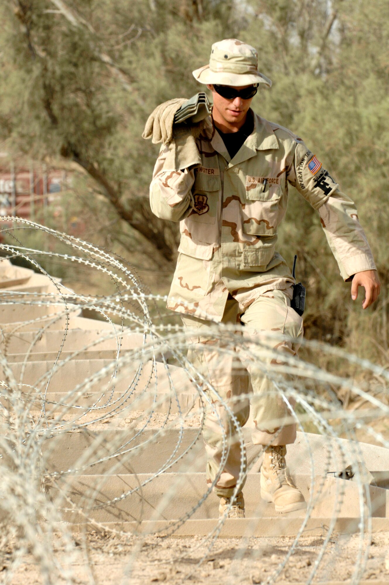 Senior Airman Brian Brewster carries stakes used to hold up the concertina wire his team is installing June 8 on a wall to protect one of the compounds on Ali Air Base, Iraq. Airman Brewster is a member of the 407th Expeditionary Security Forces Squadron's Force Protection Flight. The flight is responsible for monitoring local and third country nationals to detect suspicious activity, augmenting security forces during increased threat levels, as well as monitoring and maintaining installation security measures.(U.S. Air Force photo/Master Sgt. Robert W. Valenca)
