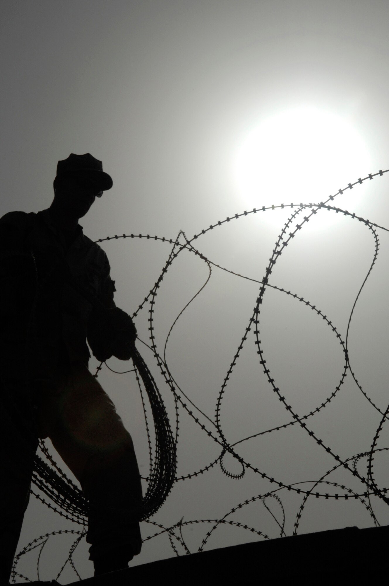 A member of the 407th Expeditionary Security Forces Squadron's Force Protection Flight carries concertina wire June 8 that his team is installing on a wall to protect one of the compounds on Ali Air Base, Iraq. The flight is responsible for monitoring local and third country nationals to detect suspicious activity, augmenting security forces during increased threat levels, as well as monitoring and maintaining installation security measures. (U.S. Air Force photo/Master Sgt. Robert W. Valenca)