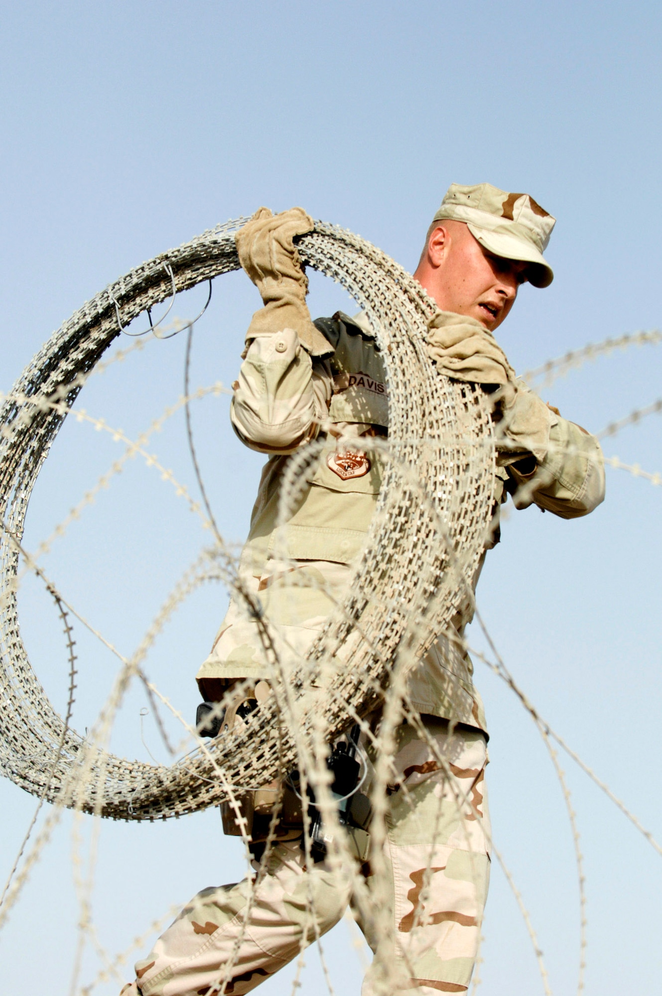 Staff Sgt. Mark Davis carries concertina wire June 8 that he and his crew are installing on a wall to protect one of the compounds on Ali Air Base, Iraq. Sergeant Davis is a member of the 407th Expeditionary Security Forces Squadron's Force Protection Flight. The flight is responsible for monitoring local and third country nationals to detect suspicious activity, augmenting security forces during increased threat levels, as well as monitoring and maintaining installation security measures. (U.S. Air Force photo/Master Sgt. Robert W. Valenca)