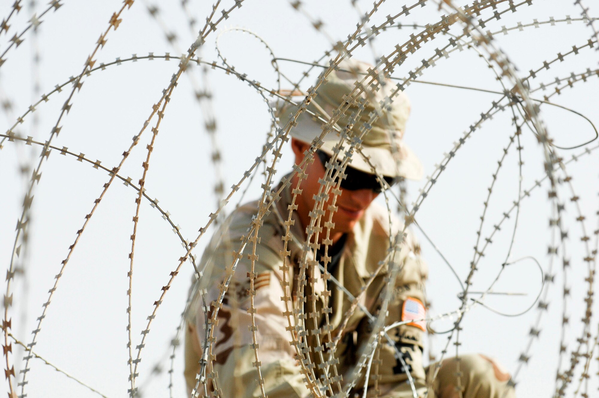 Senior Airman Brian Brewster installs concertina wire June 8 on a wall to protect one of the compounds on Ali Air Base, Iraq. Airman Brewster is a member of the 407th Expeditionary Security Forces Squadron's Force Protection Flight. The flight is responsible for monitoring local and third country nationals to detect suspicious activity, augmenting security forces during increased threat levels, as well as monitoring and maintaining installation security measures. (U.S. Air Force photo/Master Sgt. Robert W. Valenca)