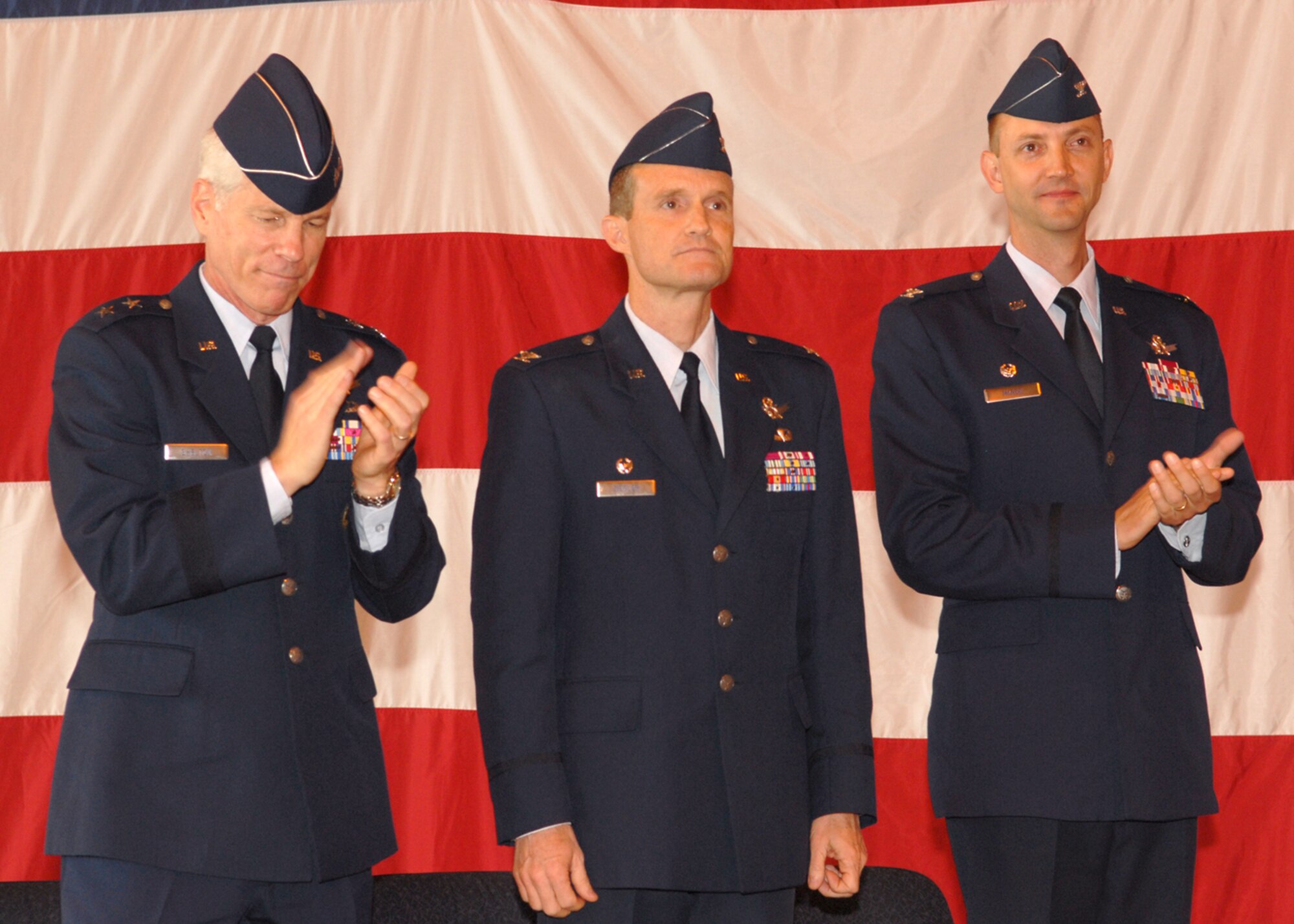 BUCKLEY AIR FORCE BASE, Colo. -- Maj. Gen. William Shelton (left), 14th Air Force commander, and Col. Donald "Wayne" McGee Jr. (right) applaud outgoing 460th Space Wing Commander Col. David W. Ziegler on his many accomplishments during his career and tenure as wing commander during a change of command ceremony June 12 at Hangar 909 here. Colonel McGee replaced Colonel Ziegler who is retiring after 25 years of service. (U.S. Air Force photo by Senior Airman LaDonnis Crump)