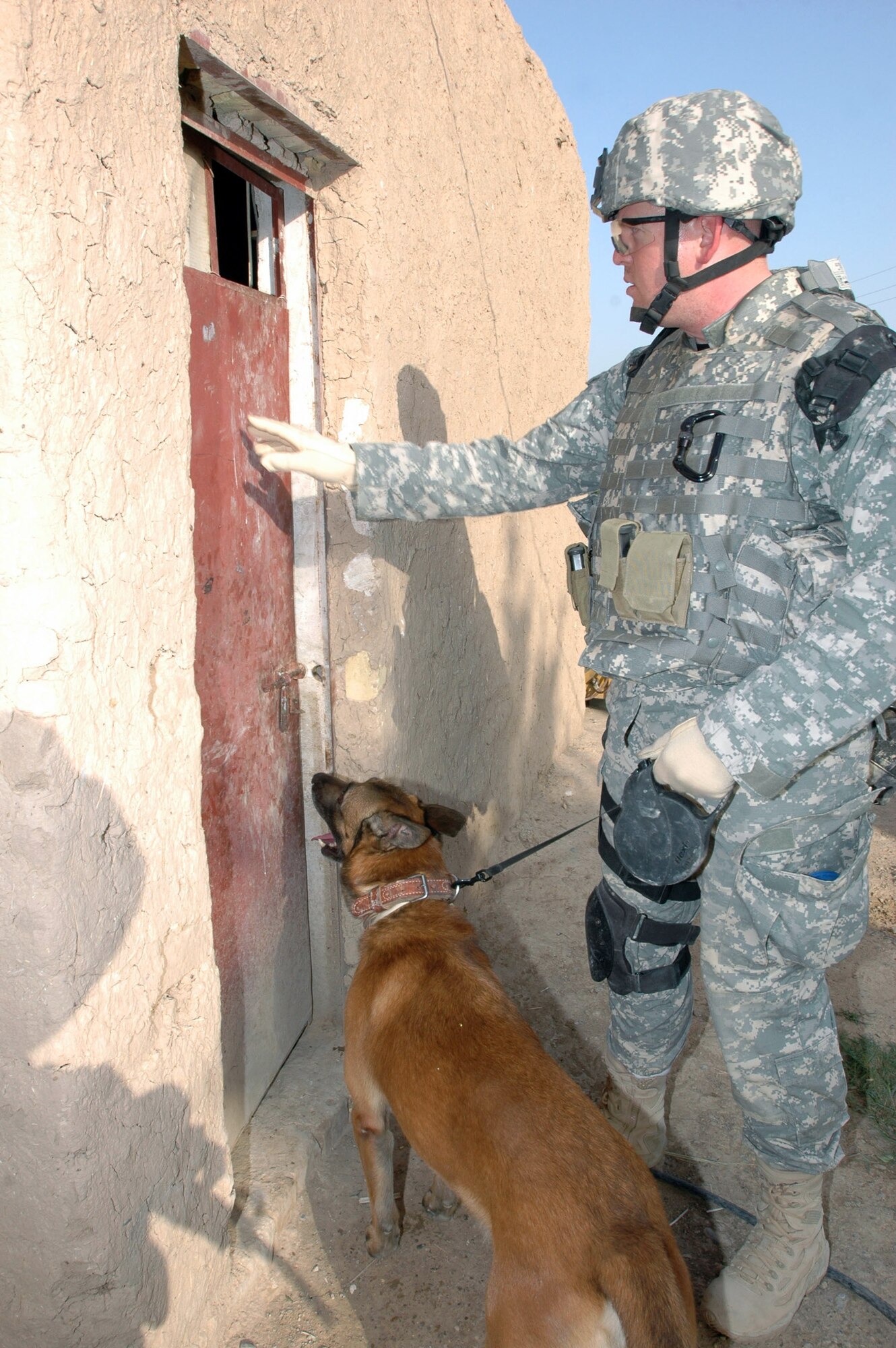 Staff Sgt. Dennis Browning, a military working dog handler, and King, an explosives and patrol attack dog, prepare to enter and search a building during a clearing operation near Khan Bani Sa'ad, about 15 miles south of Baqouba, Iraq. Sergeant Browning is deployed from the 21st Security Forces Squadron at Peterson Air Force Base, Colo. (U.S. Army photo/Sgt. Armando Monroig)