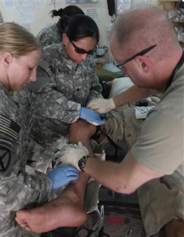 U.S. Army Spcs. Lisa Dueker (left) and Cecilia Morales provide medical aid to an Iraqi soldier wounded by gunshot in Mahmudiyah, Iraq, on June 6, 2007.  Dueker and Morales are assigned to 2nd Brigade Combat Team, 10th Mountain Division, Fort Drum, N.Y.  