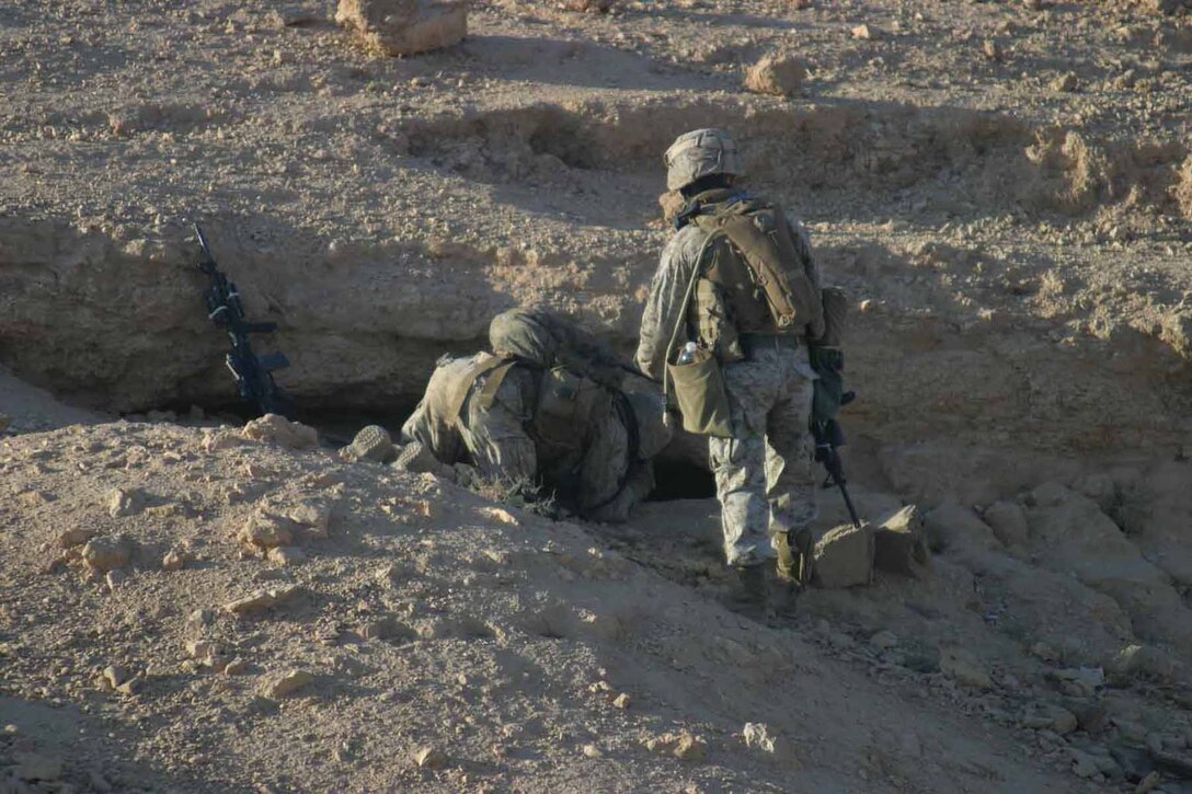 Cpl. Christopher Adamski, intelligence analyst, Charlie Company, 1/3, searches in a hole for a weapons cache in Haqlaniyah while patrolling through a wadi June 13.