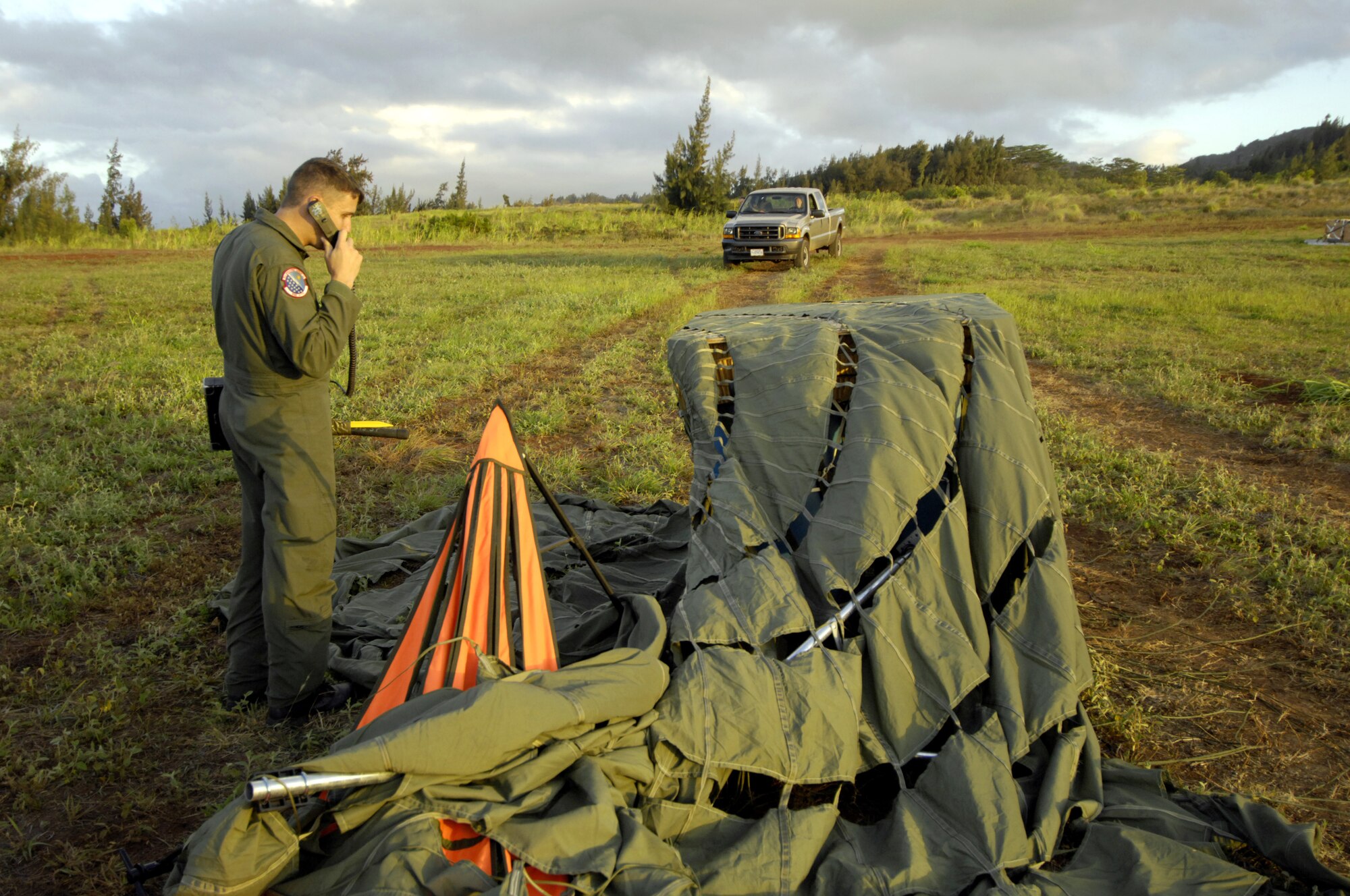 Tech. Sgt. Ken Bragg relays the landing position of a practice bundle to pilots of a C-17 Globemaster III during quarterly airdrop qualification at the Kahuku Training Range in Hawaii Monday. Sergeant Bragg is a loadmaster and drop zone control officer with the 535th Airlift Squadron, Hickam Air Force Base, Hawaii. (U.S. Air Force photo/ Tech. Sgt. Shane A. Cuomo)