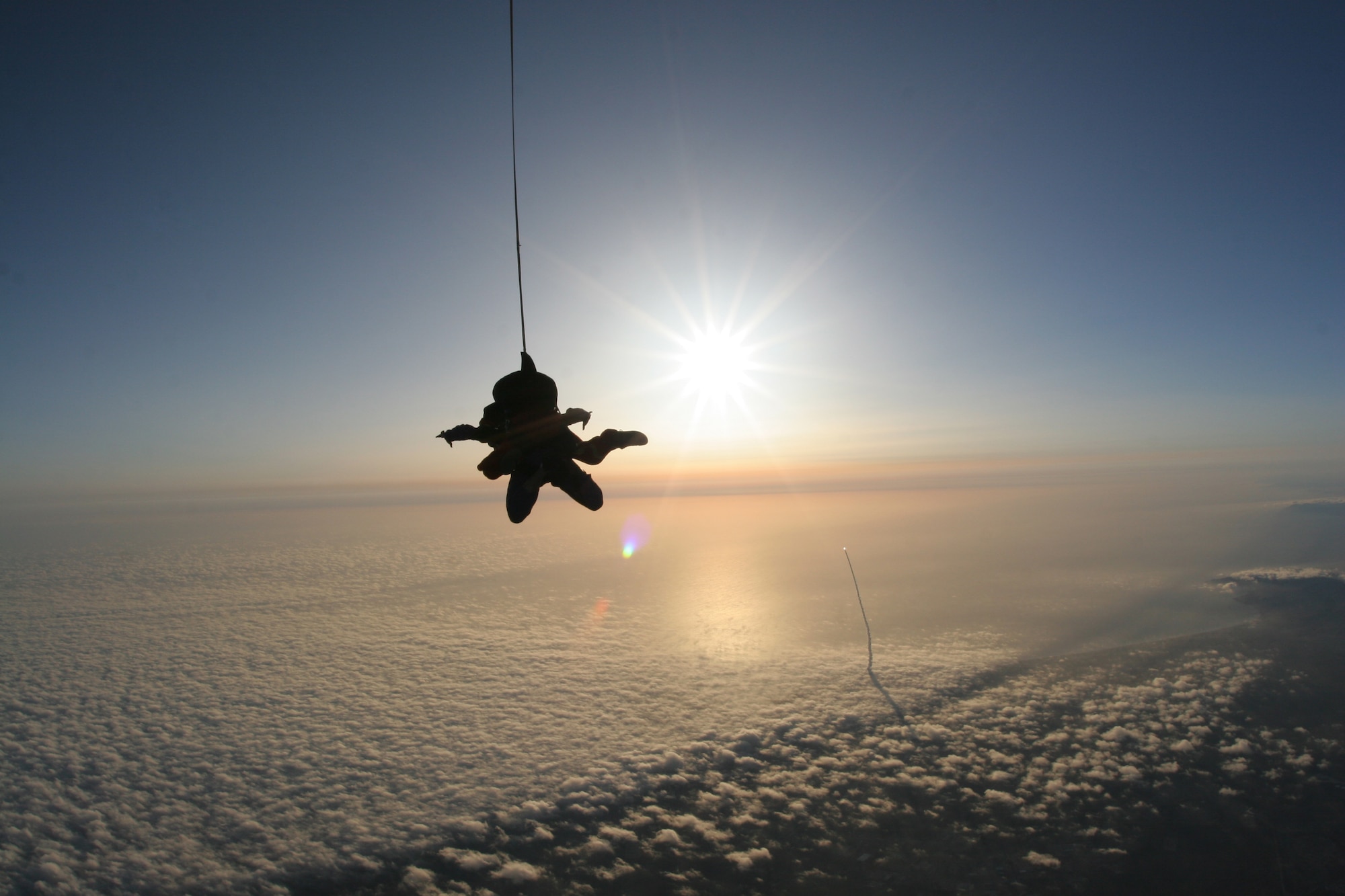 A Delta II rises above the clouds as Staff Sgt. Eric Thompson freefalls over Lompoc June 7.  The instructor with the 532nd Training Squadron planned his skydive to coincide with the launch carrying the Italian Thales Alenia-Space COSMO-SkyMed Satellite. (Courtesy photo)