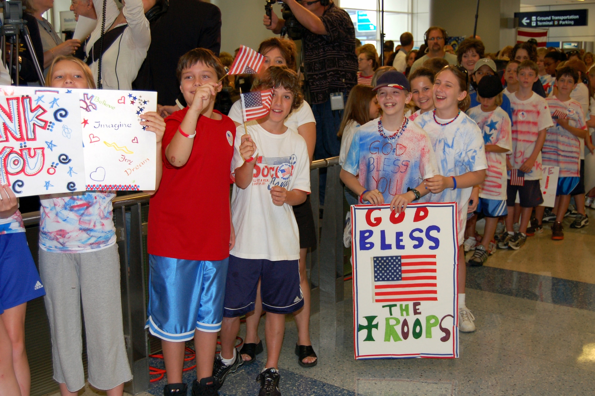 Children smile and wave U.S. flags as U.S. servicemembers prepare to pass through a greeting line of more than 400 people waiting to greet them June 12 at Dallas-Fort Worth International Airport. (U.S. Air Force photo/Tech. Sgt. John Jung) 