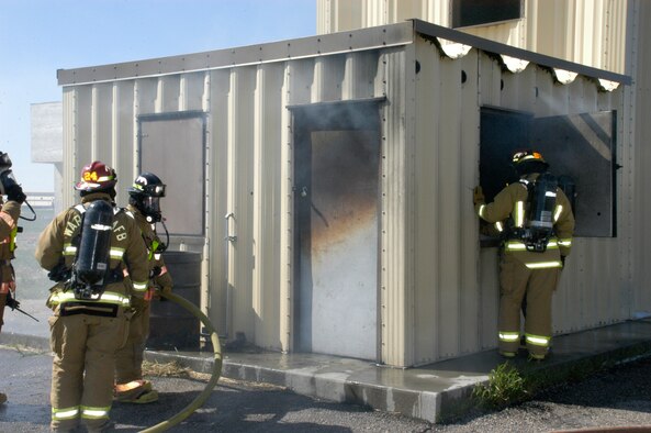Staff Sgt. Pyle, left, and Airman Colucci prepare to enter the room and fight the fire. The top half of the door is discolored because it is superheated.
