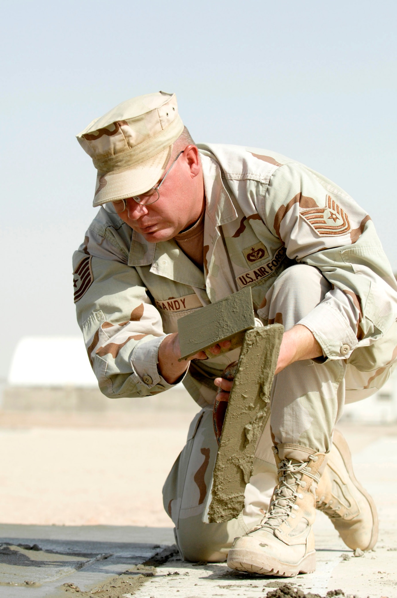 Tech. Sgt. Michael Grandy edges and floats freshly poured cement while his team builds a drill pad at Camp Mittica, Iraq, June 11. Sergeant Grandy is assigned to the 407th Expeditionary Civil Engineer Squadron at Ali Air Base, Iraq. The team is on the Iraqi base constructing a cement drill pad that will be used by the Iraqi army to train their enlisted soldiers. (U.S. Air Force photo/Master Sgt. Robert W. Valenca)
