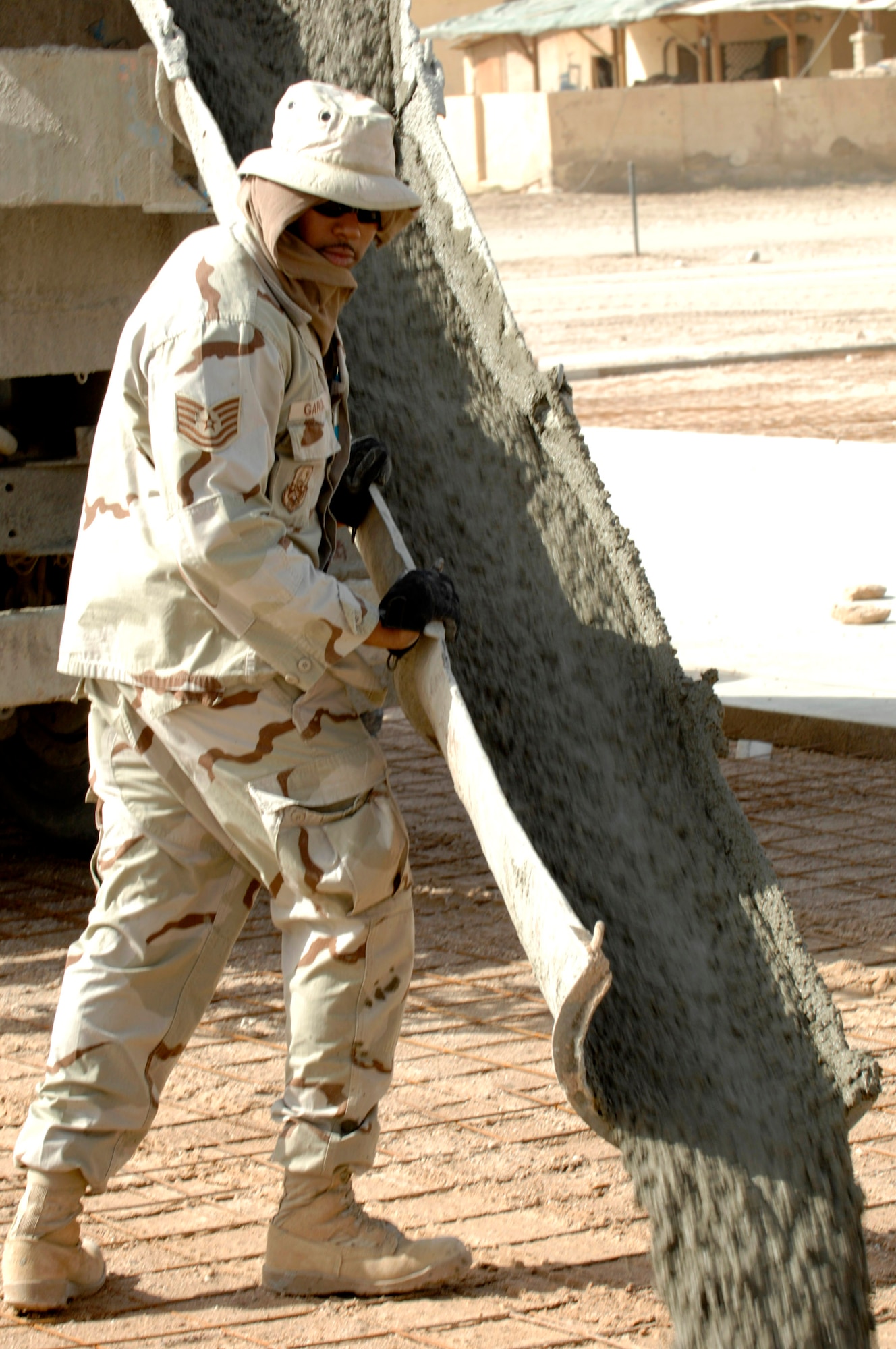 Tech. Sgt. Adenauer Garcia directs the pouring of cement from a contractor truck June 11 while building a drill pad on Camp Mittica, Iraq,. Sergeant Garcia is assigned to the 407th Expeditionary Civil Engineer Squadron. (U.S. Air Force photo/Master Sgt. Robert W. Valenca)