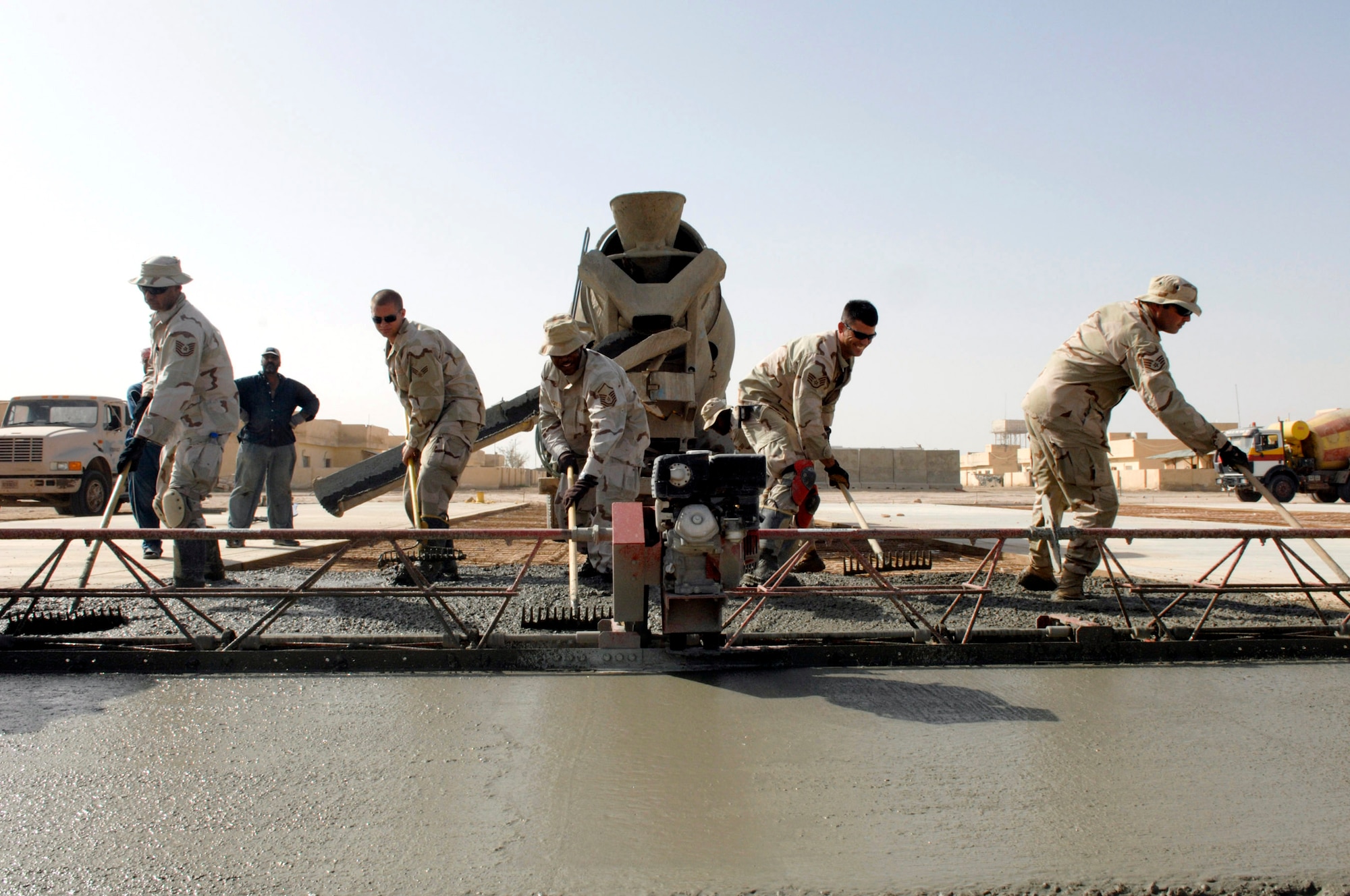 Airmen from the 407th Expeditionary Civil Engineer Squadron at Ali Air Base, Iraq, level freshly poured cement June 11 while building a drill pad at Camp Mittica, Iraq. The 407th ECES is on the Iraqi base constructing a cement drill pad that will be used by the Iraqi army to train their enlisted soldiers. (U.S. Air Force photo/Master Sgt. Robert W. Valenca)
