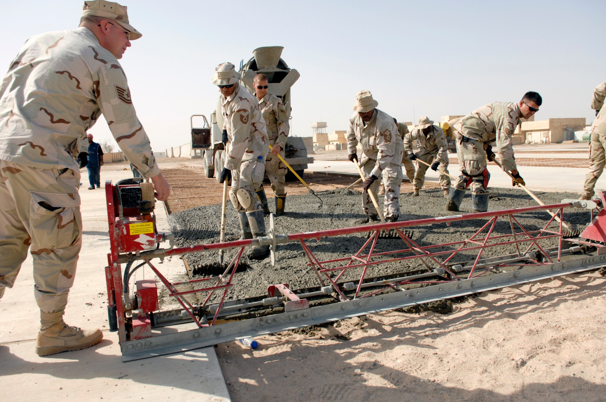 Airmen from the 407th Expeditionary Civil Engineer Squadron at Ali Air Base, Iraq, level freshly poured cement June 11 while building a drill pad at Camp Mittica, Iraq. The 407th ECES is on the Iraqi base constructing a cement drill pad that will be used by the Iraqi army to train their enlisted soldiers. (U.S. Air Force photo/Master Sgt. Robert W. Valenca) 
