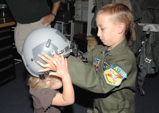 Matthew Belleau, 7, D-M's Pilot for a Day June 7, helps his 4-year-old sister try on a pilot's helmet while visiting the 358th Fighter Squadron here. Matthew, who suffers from mild cerebral palsy and ataxia, is the second local child to participate in the Pilot for a Day program at D-M so far this year. (U.S. Air Force photo/Airman 1st Class Alesia D. Goosic)