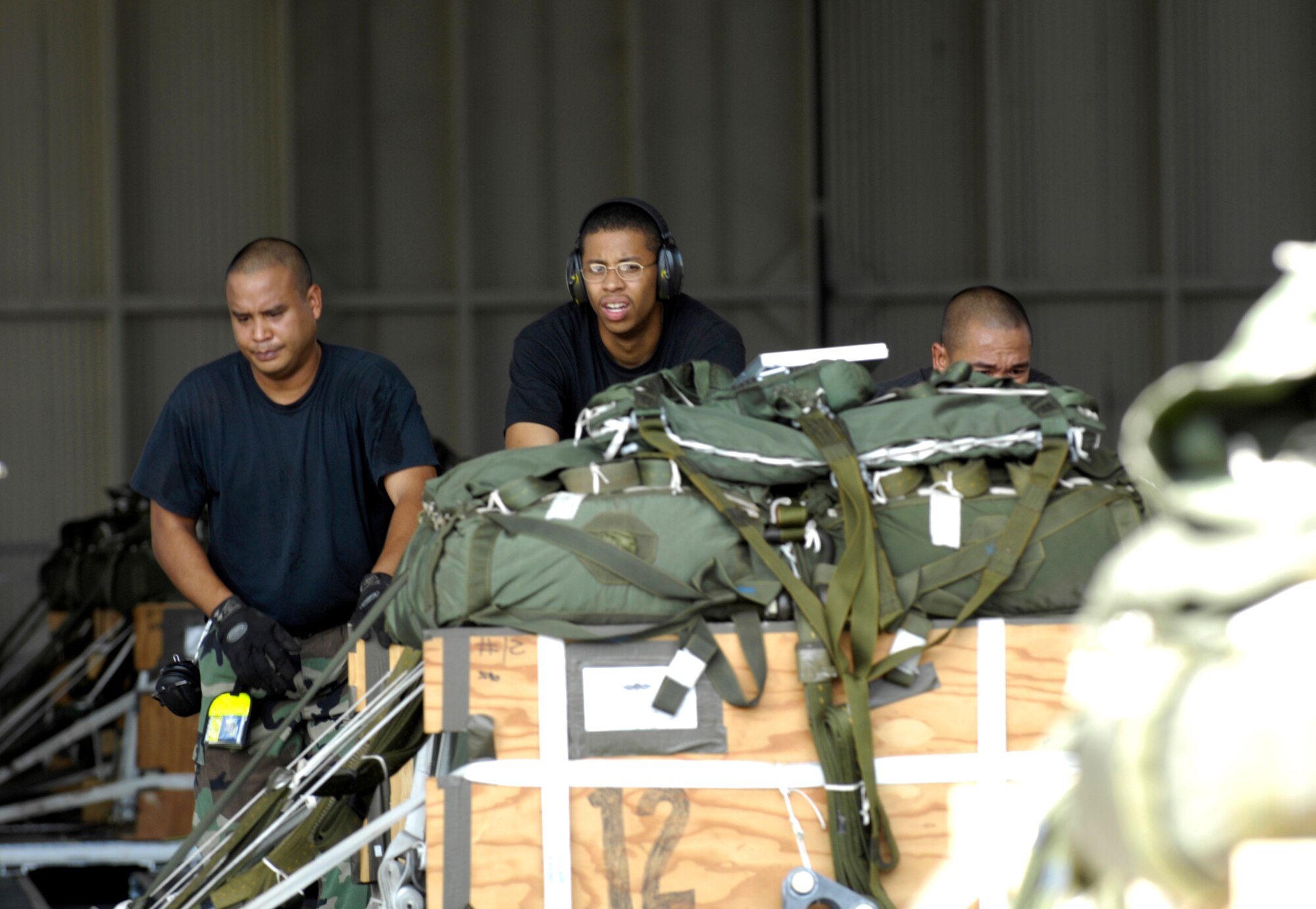 Air transportation specialists load a practice airdrop bundle onto a K-Loader at Hanger 7 at Hickam Air Force Base, Hawaii June 11, 2007. The Airmen are from the 15th Logistics Readiness Squadron Combat Mobility Element. The CME is responsible for packing and rigging all parachutes and practice bundles for airdrops at Hickam AFB. (U.S. Air Force photo/ Tech. Sgt. Shane A. Cuomo)

