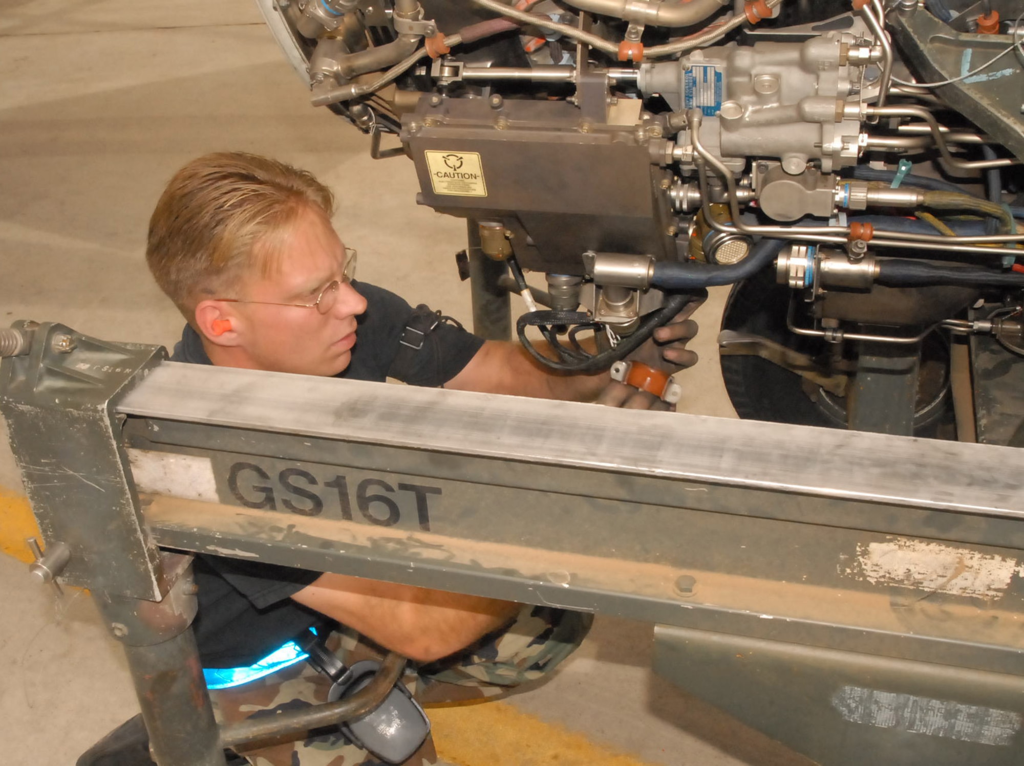 Staff Sgt. Wesley Coll, 62nd Aircraft Maintenance Unit dedicated crew chief, removes a spider harness Monday from the bottom of an F-16 Fighting Falcon engine. The spider harness is a bundle of wires which connects from the aircraft to the engine. Photo by Phillip Butterfield