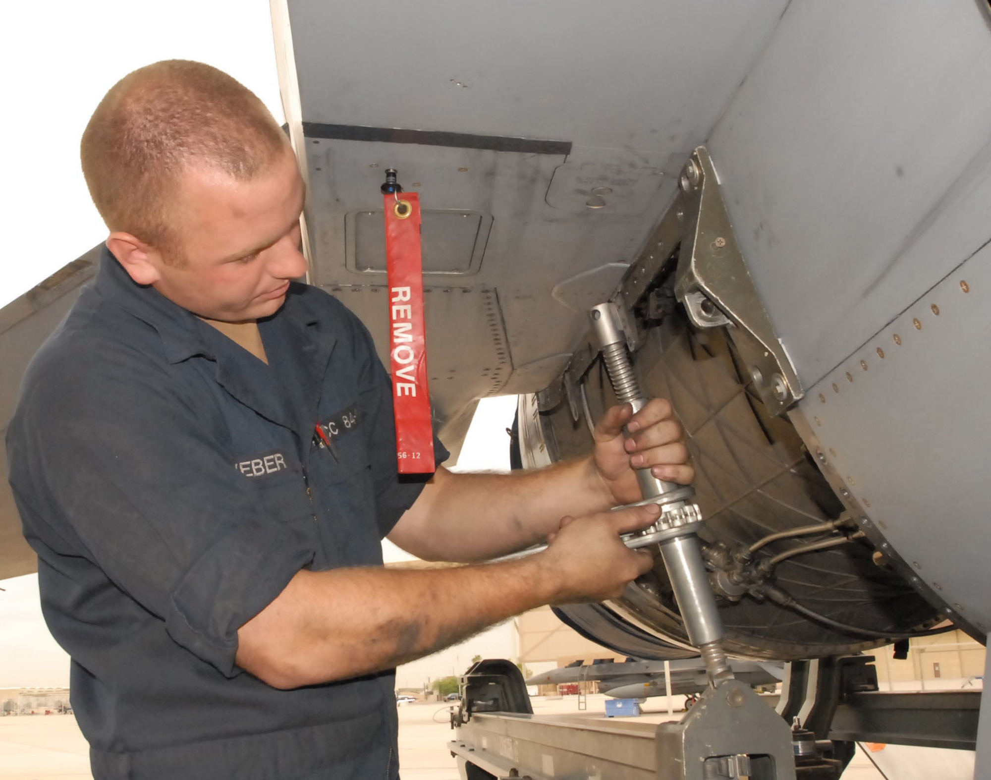 Airman 1st Class Nicholas Weber, 62nd Aircraft Maintenance Unit assistant dedicated crew chief, bolts an engine removal and installation trailer Monday to an F-16 Fighting Falcon in preparation to remove the engine. Photo by Staff Sgt. Phillip Butterfield 
