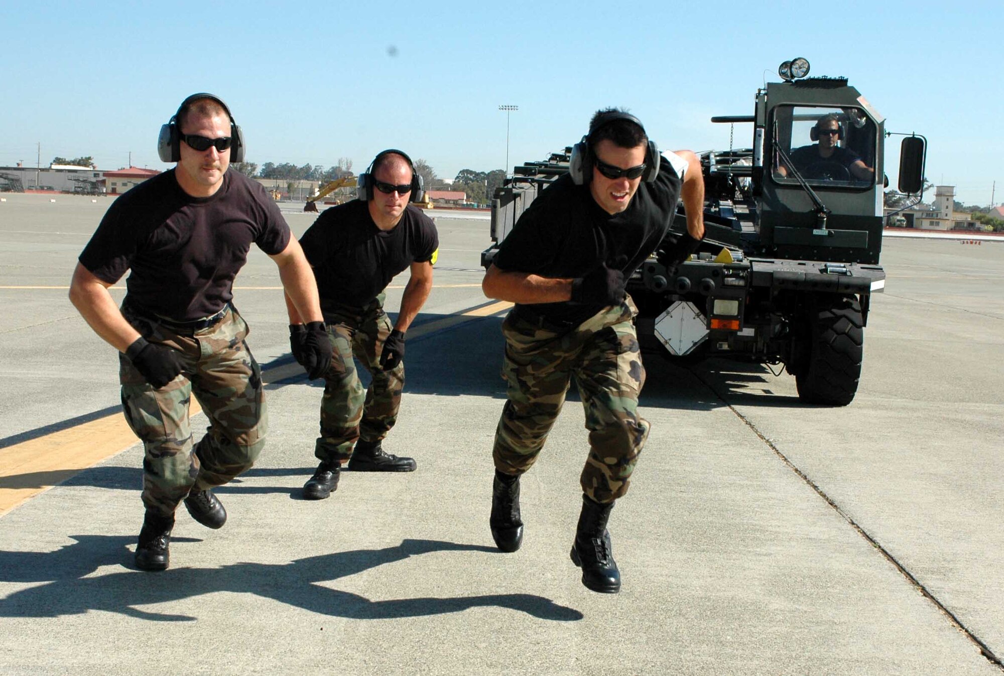 From left to right: Staff Sgt. Joseph Chilton, Senior Airman Brian Harmon, Airman 1st Class Dan Levindofske, make a running dash toward a C-5 Galaxy, while K-Loader driver Staff Sgt. Mark Hoffman drives a K-Loader to it's starting position, during a C-5 engine running on/offload practice June 11. The Airmen are members of the 60th Aerial Port Squadron’s Rodeo team. (U.S. Air Force photo by Staff Sgt. Candy Knight)