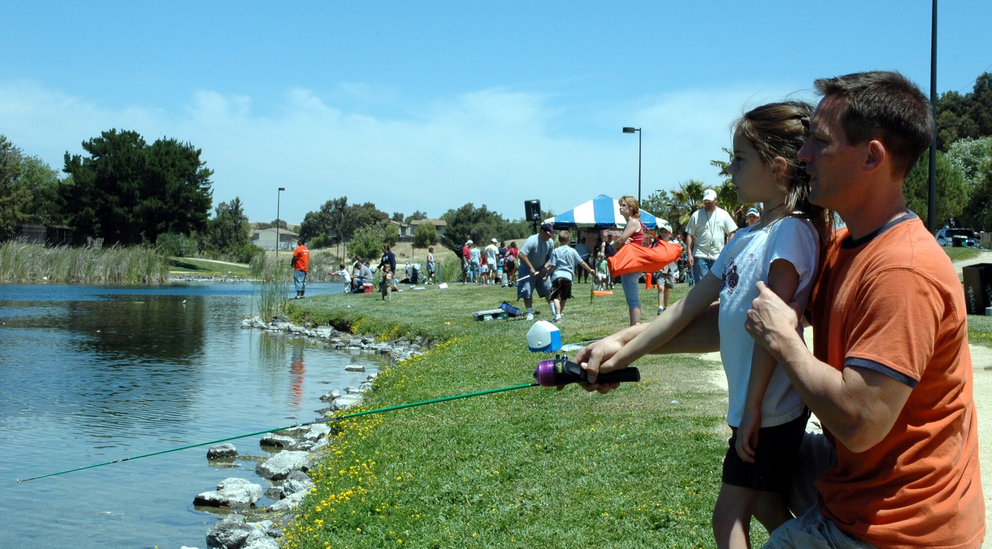 Maj. Greg Green, 60th Air Mobility Wing executive officer, helps his daughter Isabel, age 5, cast during the Fishing Derby at the Duck Pond June 9. (U.S. Air Force photo by Tech. Sgt. Donald Osborn)