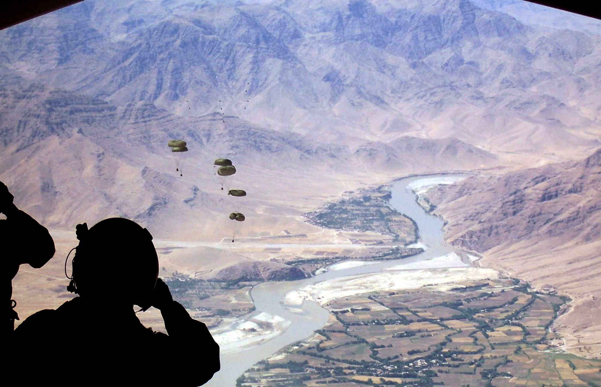 Staff Sgt. Derek Howard, an 816th Expeditionary Airlift Squadron evaluator loadmaster, watches cargo bundles fall over a dropzone in Afghanistan. (U.S. Air Force photo/Capt. Teresa Sullivan)