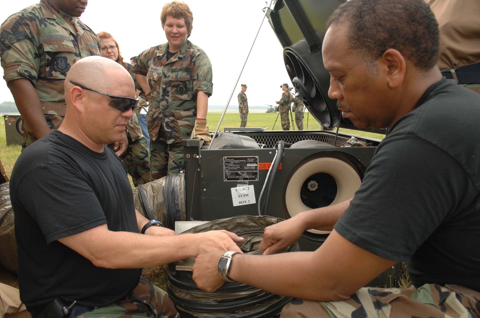 U.S. Air Force TSgt Ron Davis (left), Medical Readiness Instructor, 381st Training Squadron, Sheppard AFB, Texas, and MSgt Ernest Farmer (right), Mental Health Technician, 94th Air Lift Wing/ Aeromedical Staging Squadron, Dobbins ARB, Ga., work together to fit an air filter onto the duct of an environmental control unit for a medical tent during exercise Golden Medic on June 11, 2007. Golden Medic is a yearly medical exercise sponsored by the U.S. Army Reserve designed to provide a realistic training experience to participating combat support and service support units, while enhancing the overall training and readiness of Army Reserve and Air Force medical units. (U.S. Air Force photo by Senior Airman Erica J.Knight)(RELEASED)