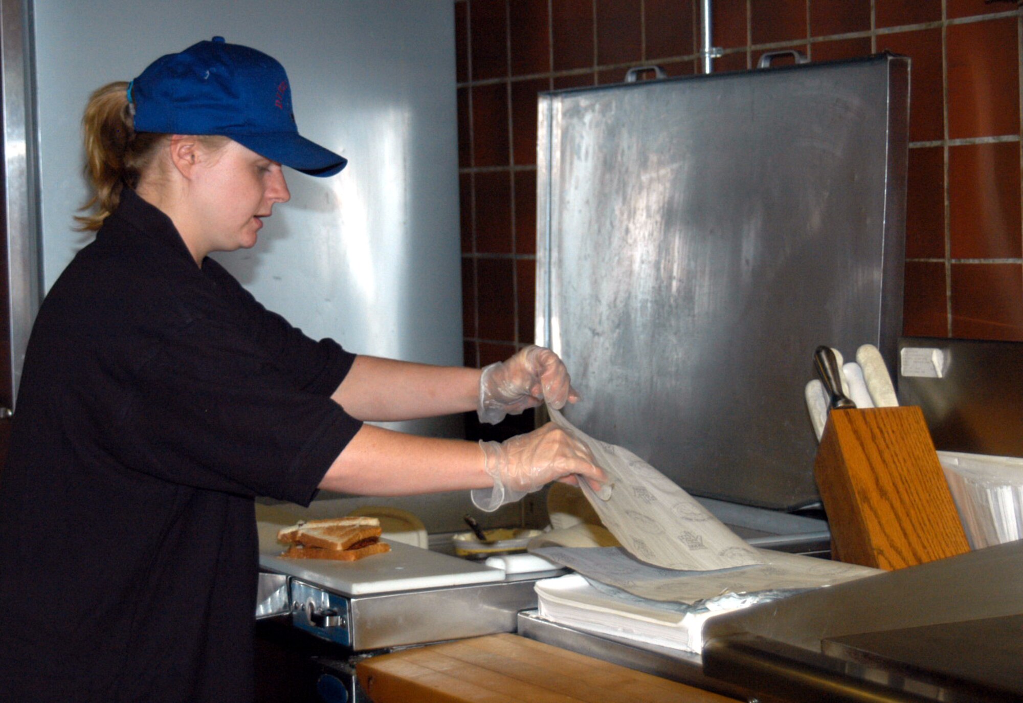 Nikki Decicco, Dyess Lanes' food and customer service employee, prepares a sandwich for a customer in the old kitchen facilities June 12. The bowling alley will close July 9 for $750,000 renovations, including the 'Deadwood Cafe' where visitors may choose from an entirely re-vamped menu. (U.S. Air Force photo/Airman 1st Class Carolyn Viss)                                