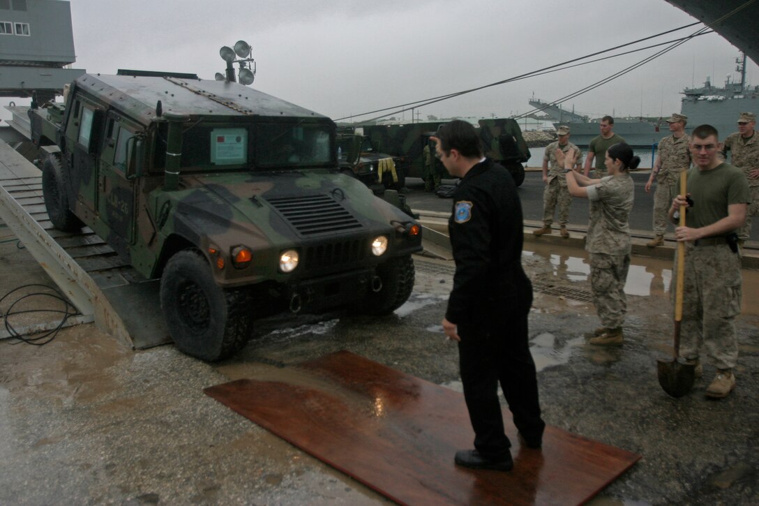 A United States customs inspector looks on as a 26th Marine Expeditionary Unit humvee backs up onto a wash rack June 15, 2007, at Naval Station Rota, Spain.  The 26th MEU is preparing to return to Camp Lejeune following their six-month deployment in support of the Global War on Terror.