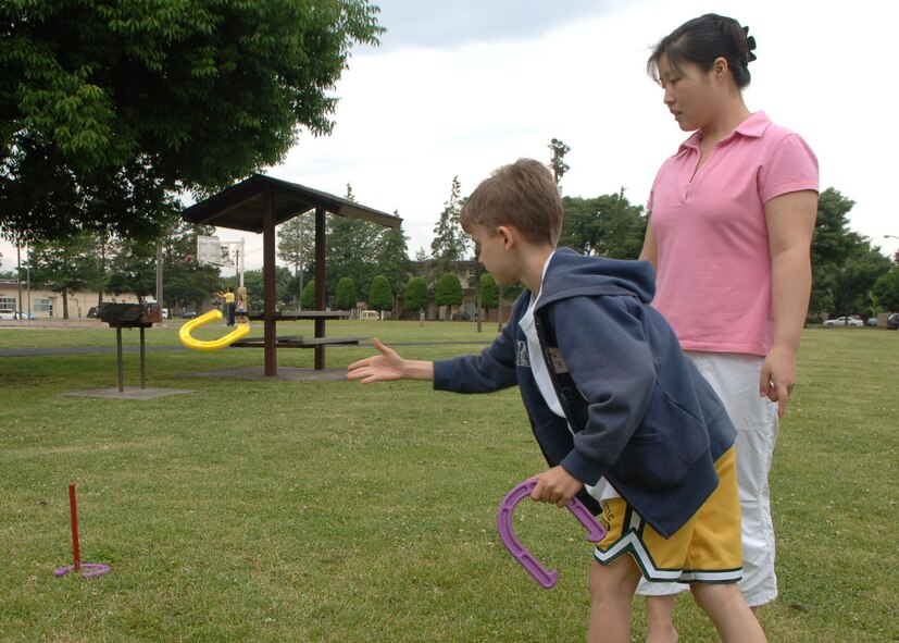 Volunteer A1C Emily Hong, 374th Mission Support Squadron, plays horse shoes with Jordan Schultz, son of  Tech Sgt. Robert Schultz,  during a families of deployed members picnic. Events are held monthly by the Air Force Family Readiness Center here to provide the support needed for those families left behind during deployments. (U.S. Air Force photo by Senior Airman Veronica Pierce)