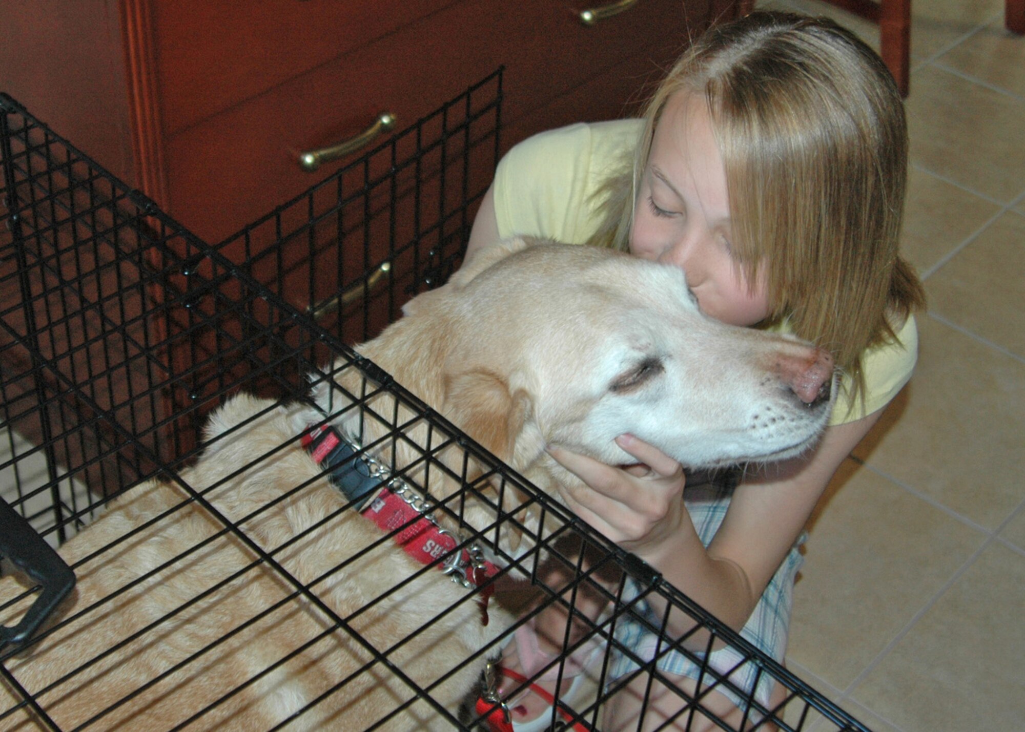EIELSON AIR FORCE BASE, Alaska--Dana Panfil, daughter of Master Sgt. Michael and Sue Panfil, gives family dog Dusty a smooch on the cheek before tucking him in the new kennel in military family lodging June 14. Four pet-friendly rooms in The Goldrush Inn were furnished with a kennel, water and food bowls and a pooper-scooper. Families are allowed up to two canine and/or feline pets at a time; any caged animal 20 pounds or less must be pre-approved before your stay. For more information on the new pet policy, call 377-1844. (U.S. Air Force photo by Airman 1st Class Nora Anton)