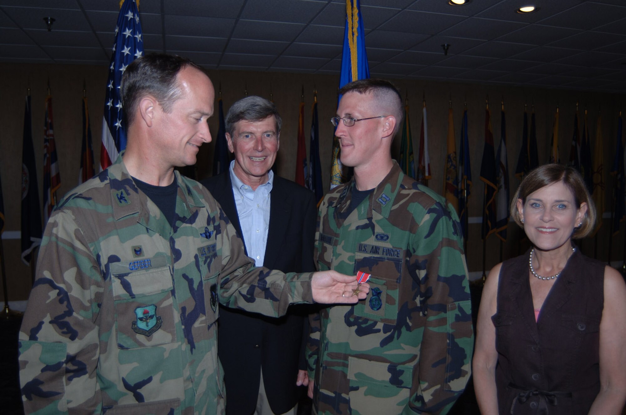 Colonel Dave Gerber, 14th Flying Training Wing Commander, pins a Bronze Star on Captain Kevin McMahon, 14th Security Forces Squadron, for actions rendered during his deployment to Iraq.  In this photo, Capt. McMahon is accompanied by his father, Tim, and his mother, Carolyn. (U.S. Air For ce Photo by 2nd Lt. Justin Jarrell)