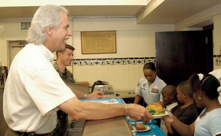Dave Saylor, honorary commander of the 322nd Training Squadron, Maj. Rob Passinault, 322nd TRS commander, and Tech. Sgt. LaTanya Dinkins, 322nd TRS military training instructor, serve an evening snack to Alexis Brown, front, Atrious Carter and Kyree Brown at the Laurel Heights Youth Center June 7 as part of the No Child Left Behind program. The honorary commander program provides local community leaders an opportunity to see the inner workings of the Air Force mission and culture. The 322nd TRS regularly serves meals to students in after-hours school classes and programs. (USAF photo by Staff Sgt. Brian Hansberry)                              