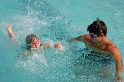 Kayla Kolua, 7, shows her swim instructor, Josh Noble, how well she knows how to swim at the base pool June 12.  (U.S. Air Force photo/ Staff Sgt. April Quintanilla)
