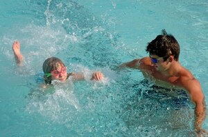 Kayla Kolua, 7, shows her swim instructor, Josh Noble, how well she knows how to swim at the base pool June 12.  (U.S. Air Force photo/ Staff Sgt. April Quintanilla)