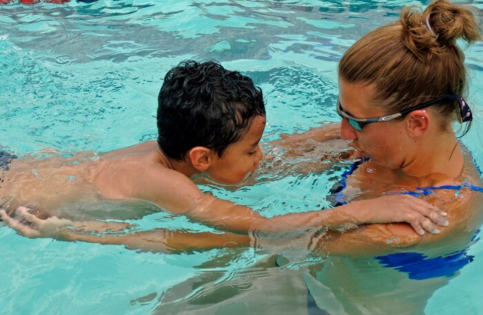 Xavier Muniz, 6, holds onto Allison Fleifchauer, head life guard and swim instructor, as she teaches him to put his face in the water and blow bubbles as he swims at the base swimming pool June 12.  (U.S. Air Force photo/Staff Sgt. April Quintanilla)