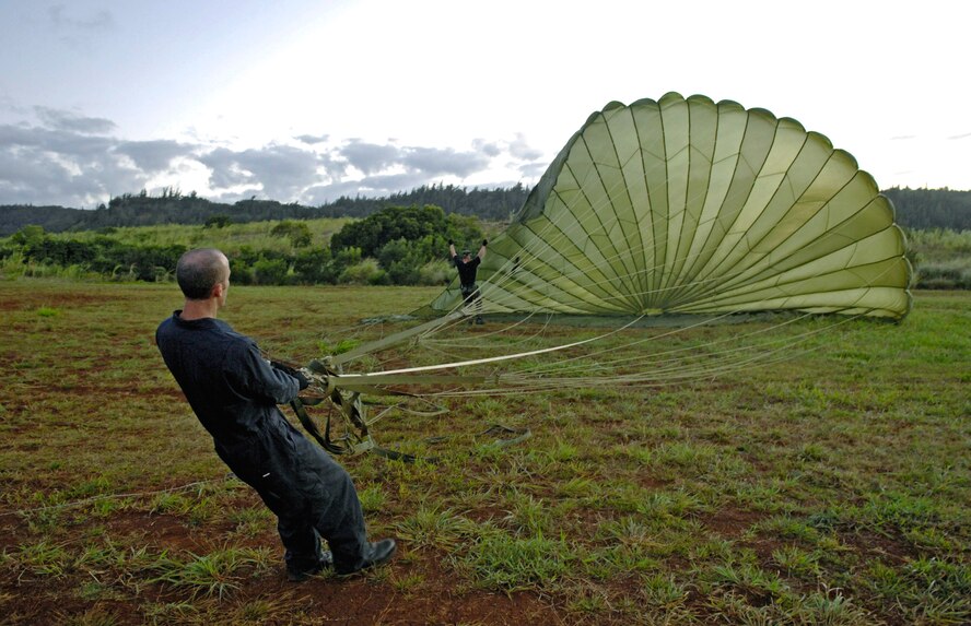 Tech. Sgt. Ralph Plummer and Staff Sgt. Robert Ward collect a parachute from a practice airdrop bundle which was dropped from a C-17 Globemaster III June 11 at the Kahuku Training Range in Hawaii. The C-17s, from the 535th Airlift Squadron at Hickam Air Force Base, are conducting their quarterly airdrop qualifications. The Airmen are air transportation specialist from the 15th Logistics Readiness Squadron Combat Mobility Element. (U.S. Air Force photo/ Tech. Sgt. Shane A. Cuomo) 