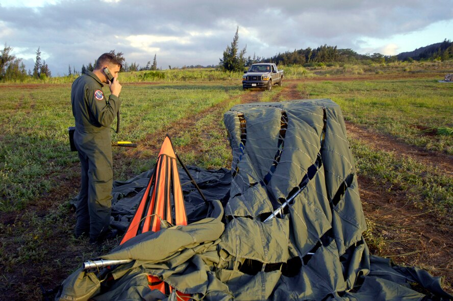 Tech. Sgt. Ken Bragg relays the landing position of a practice bundle to pilots of a C-17 Globemaster III during quarterly airdrop qualifications June 11 at the Kahuku Training Range in Hawaii. Sergeant Bragg is loadmaster and drop zone control officer with the 535th Airlift Squadron at Hickam Air Force Base. (U.S. Air Force photo/ Tech. Sgt. Shane A. Cuomo)