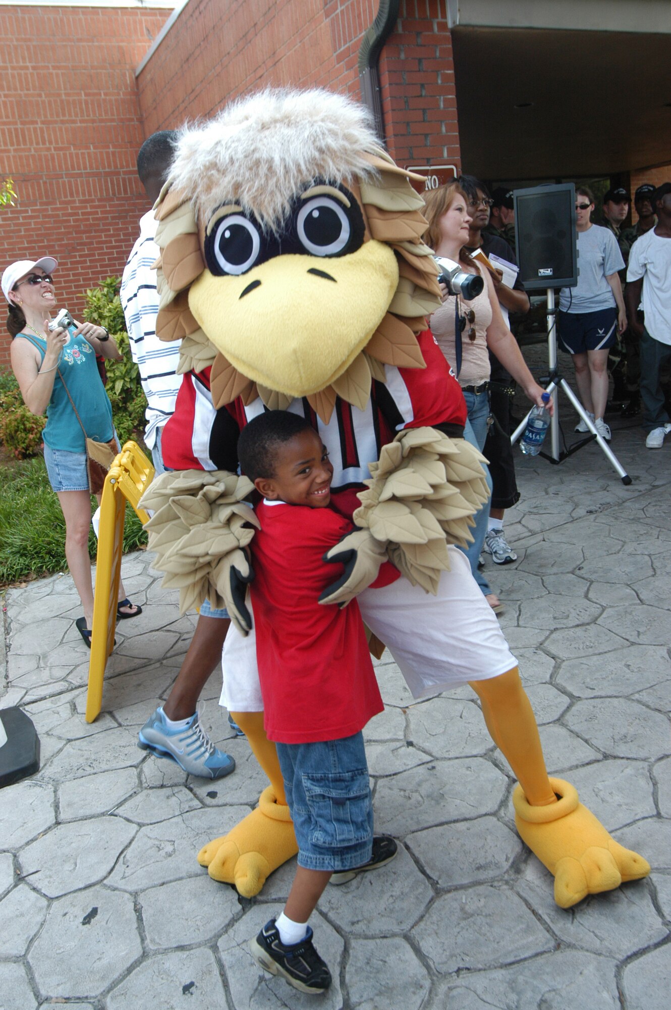 Javian Wimes, 5, gets a hug from Freddie Falcon. U. S. Air Force photo by Sue Sapp        