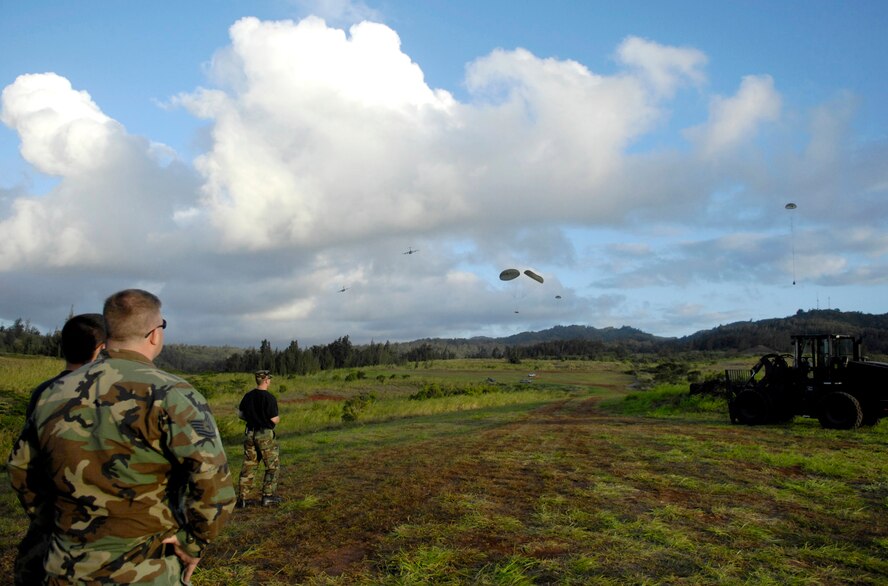 Air transportation specialists watch the 535th Airlift Squadron's C-17 Globemaster IIIs run quarterly airdrop qualifications June 11 at the Kahuku Training Range in Hawaii. The Airmen who had loaded the cargo bundles are from the 15th Logistics Readiness Squadron Combat Mobility Element and the C-17s are from Hickam Air Force Base, Hawaii. (U.S. Air Force photo/ Tech. Sgt. Shane A. Cuomo) 
