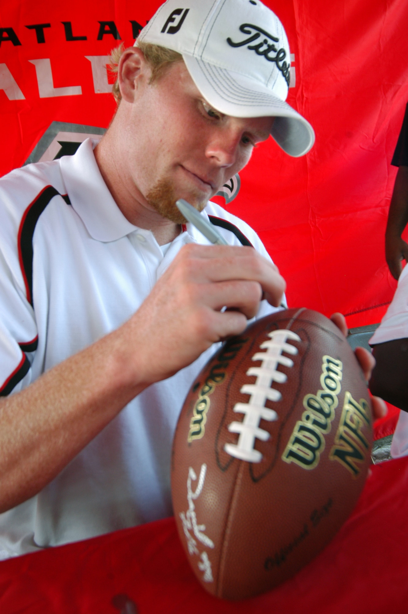 Boone Stutz, Atlanta Falcon long snapper, signs a football for a fan. U. S. Air Force photo by Sue Sapp   