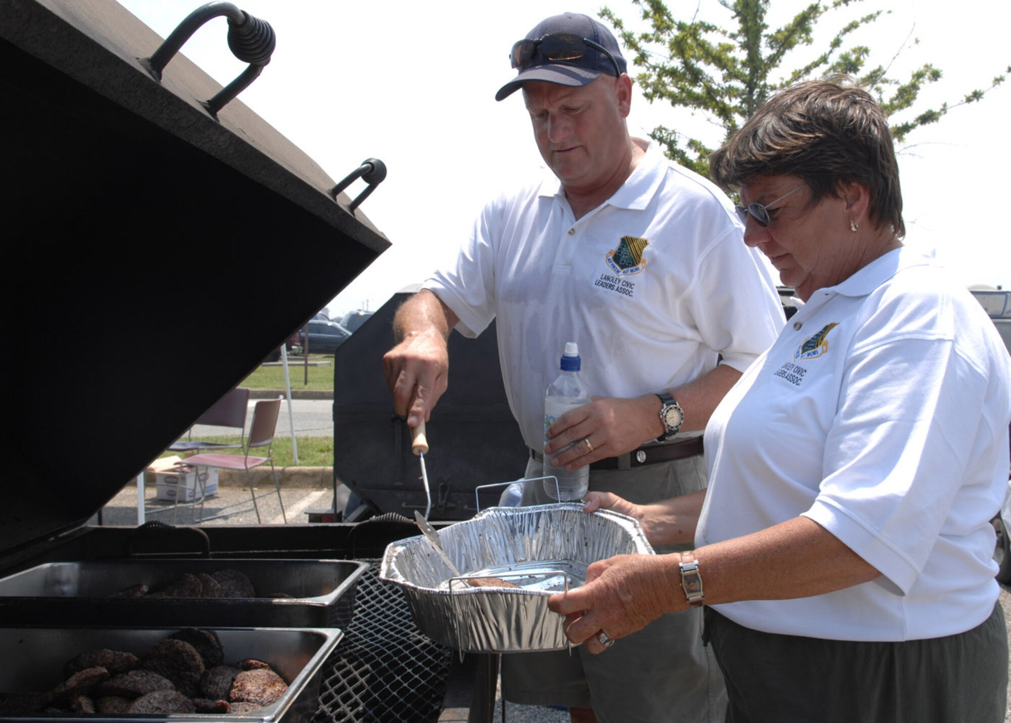 Langley Civic Leaders Association members Steve Mallon and Dale Drumright lend a hand by grilling hamburgers here during Junior Enlisted Appreciation Day June 8. The all-day event was a tribute to the dedication of Langley Airmen.  (U.S. Air Force photo/Staff Sgt. Katrina Shellman)