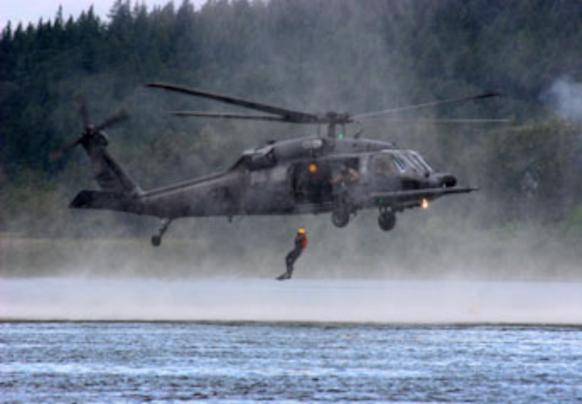 While a HH-60 Pavehawk helicopter comes in low and slow over the Columbia River near Portland Ore., pararescuemen from the 304th Rescue Squadron jump into the river during a water rescue scenario June 11, 2007.  (U.S. Air Force Photo/Ruby Zarzyczny)