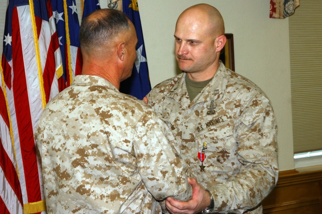 MARINE CORPS BASE CAMP LEJEUNE, N.C. - Major Gen. Robert C. Dickerson, the commanding general of Marine Corps Installations East, presents Capt. Walter D. Romine Jr. with a Bronze Star Wednesday in Bldg. 1. While serving as the Explosive Ordnance Disposal Platoon Commander for Combat Service Support Battalion-1, 1st Marine Logistics Group, I Marine Expeditionary Force from March to September 2004 in support of Operation Iraqi Freedom II, Romine was instrumental in disposing of more than 156,000 pounds of explosives, nearly 50,000 rounds of small arms ammunition and more than 100 missiles. Photo by:  Lance Cpl. Adam Johnston