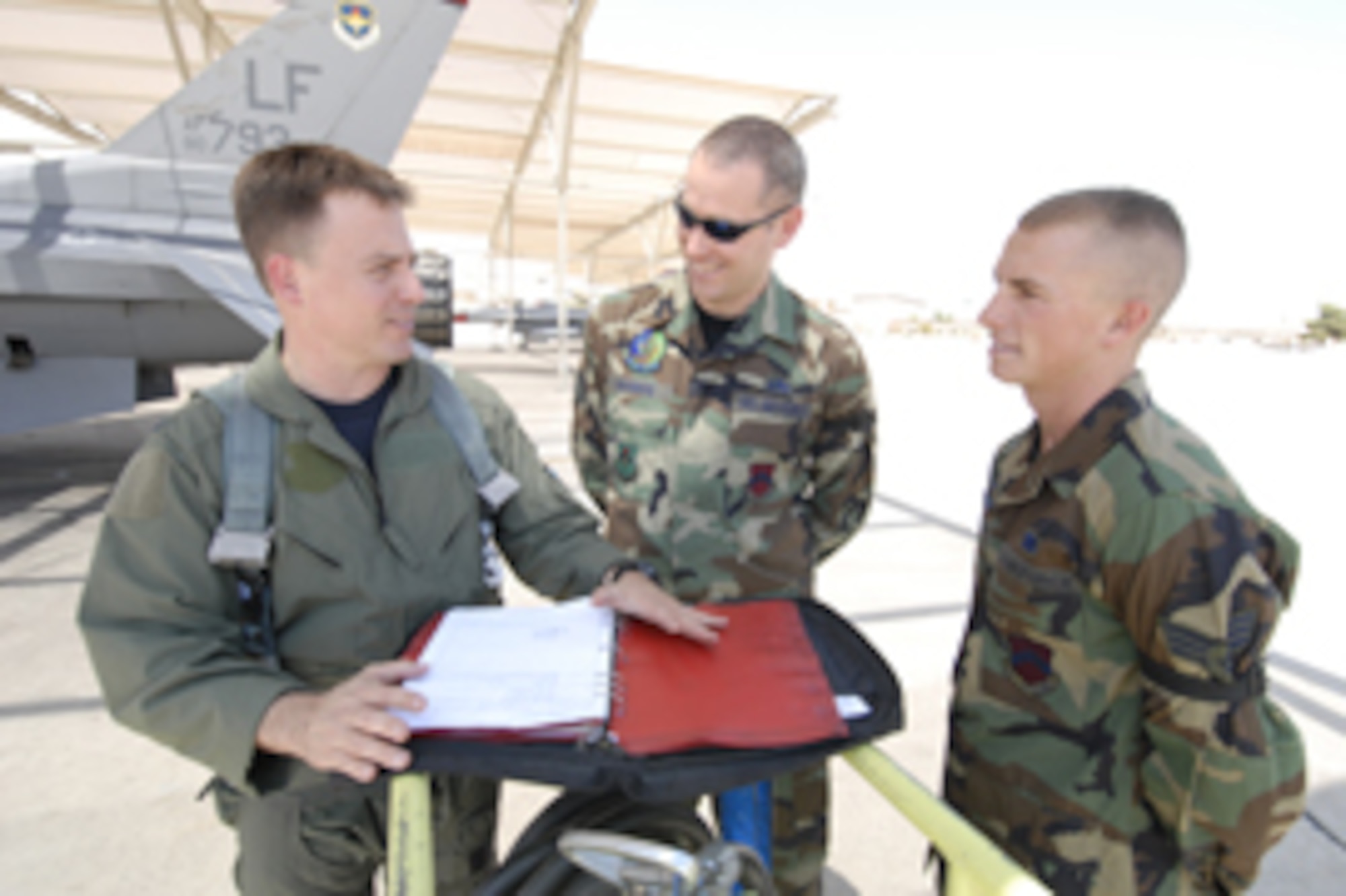 Col. Robert Givens, 56th Operations Group commander, reviews aircraft forms with Staff Sgt. Shawn Manning, center, and Senior Airman Jacob Spiller, 309th Aircraft Maintenance Unit crew chiefs, prior to flight Wednesday.  Photo by Staff Sgt. David Miller