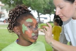 Dishan Hayes gets her face painted with camoflauge during the Operation Families Learning About Global Support event June 8 on base. (U.S. Air Force photo by Rich McFadden)