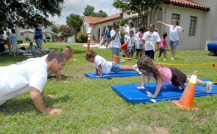Operation FLAGS volunteers show children how to do pushups as part of an obstacle course at the event. (U.S. Air Force photo by Rich McFadden)
