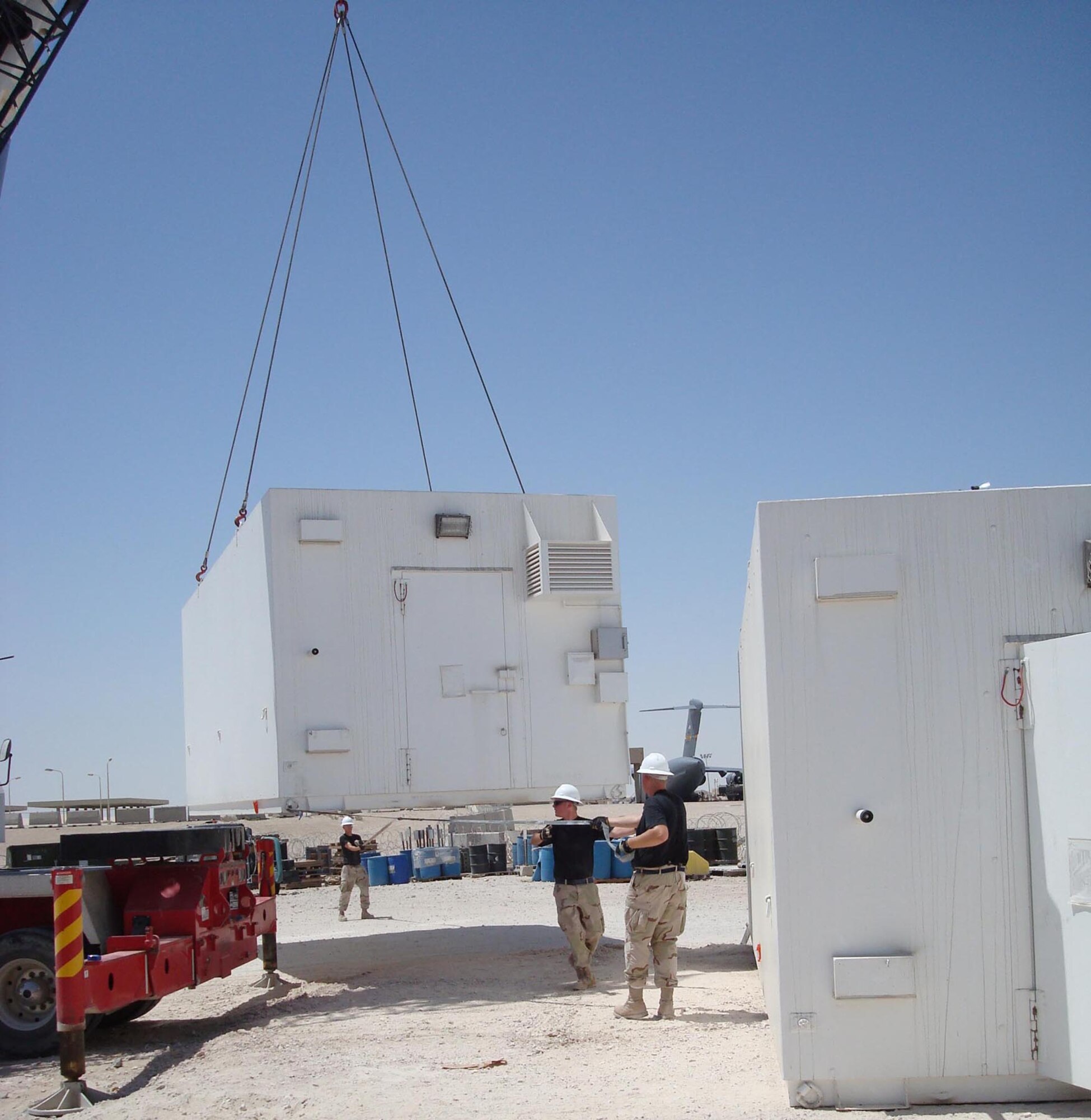 Members of the 379th Air Expeditionary Wing help place and set up two portable armories on base. The new armories will allow the 379th Expeditionary Logistics Readiness Squadron to streamline operations at one of the two current armory locations, and combine their operations at a single armory location. (U.S. Air Force photo by 1st Lt. Steve Moore)          